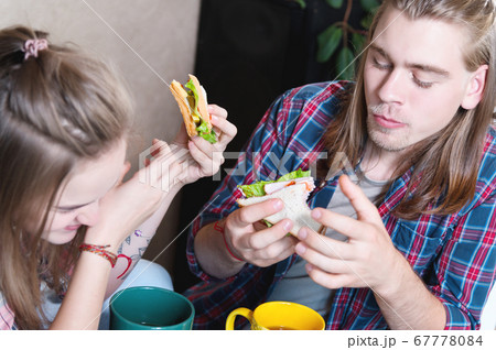 A young attractive couple has breakfast in their home kitchen. They feed each other and laugh. The concept of healthy eating in the family and happiness 67778084