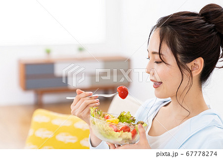 自宅のソファでサラダを食べる若い女性 67778274