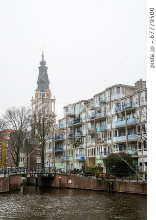 オランダアムステルダムの街並み 運河沿いの近代的な建物と歴史的な大きな時計台の写真素材