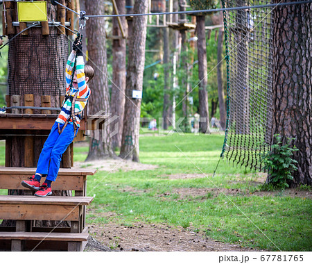 smiling boy rides a zip line. happy child on the smiling boy rides a zip line. happy child on the 67781765