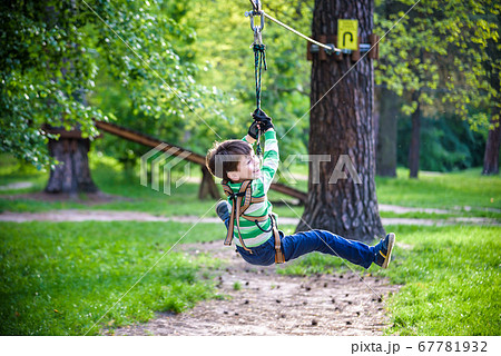 smiling boy rides a zip line. happy child on the 67781932