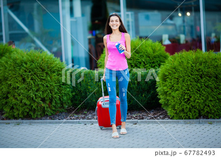 Vacation. Smiling female passenger proceeding to exit gate pulling suitcase through airport concourse. Vacation. Smiling female passenger proceeding to exit gate pulling suitcase through airport concourse. 67782493