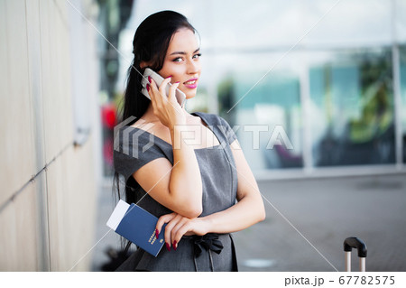 Travel. Business Woman in airport talking on the smartphone while walking with hand luggage in airport going to gate 67782575
