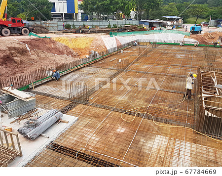 KUALA LUMPUR, MALAYSIA -MARCH 3, 2020: Building floor slab under construction. Construction workers fabricating the timber formwork and installing the steel reinforcement bar. KUALA LUMPUR, MALAYSIA -MARCH 3, 2020: Building floor slab under construction. Construction workers fabricating the timber formwork and installing the steel reinforcement bar. 67784669