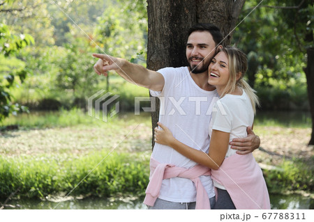 caucasian couple in sport wear hugging in the park while boyfriend pointing something 67788311