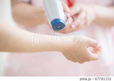 医療　非接触体温計で検温する看護師（手元） 67791152