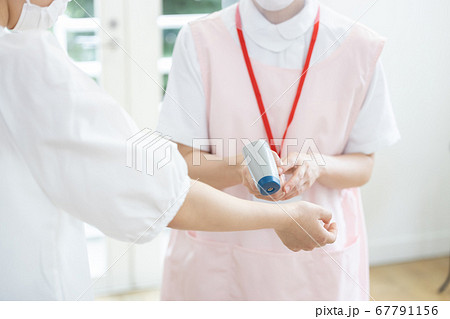 医療　非接触体温計で検温する看護師（手元） 67791156