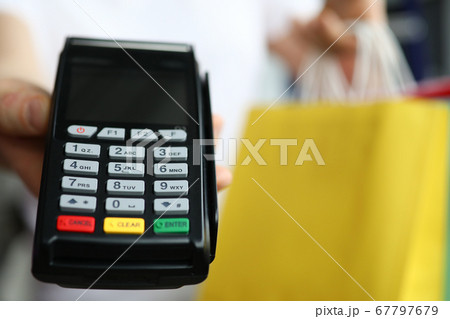 Man hold cash register close up on background of packages with purchases. Man hold cash register close up on background of packages with purchases. 67797679