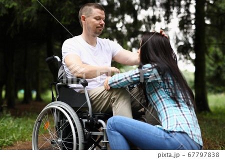 Distressed man sit in wheelchair and strokes girl on head. Distressed man sit in wheelchair and strokes girl on head. 67797838