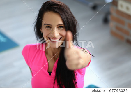 Beautiful happy girl sit on gymnastic mat in gym and show thumb up. Beautiful happy girl sit on gymnastic mat in gym and show thumb up. 67798022