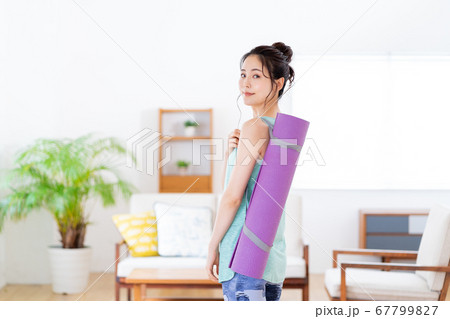 リビングでヨガマットを持つ若い女性 67799827
