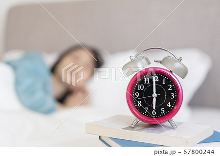 睡眠中の女性のそばに置かれた目覚まし時計 睡眠中の女性のそばに置かれた目覚まし時計 67800244