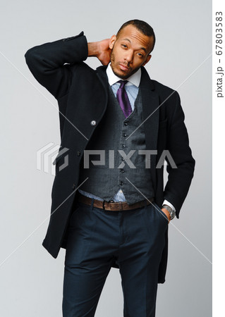 studio shot of a african-american businessman wearing coat over light grey background 67803583