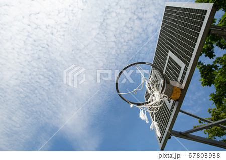 A broken basketball net dangles from a hoop attached to a metal backboard.  67803938