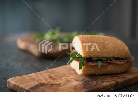 Ciabatta sandwich with salame, arugula, red pesto and cream cheese on olive board Ciabatta sandwich with salame, arugula, red pesto and cream cheese on olive board 67804237