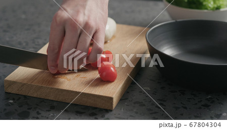 man slicing cherry tomatoes on oak board 67804304