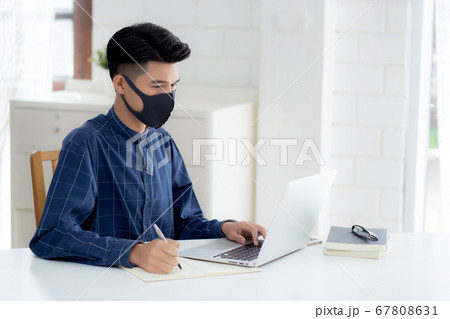 Young asian business man in face mask for protect covid-19 and work on laptop computer. 67808631