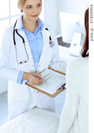 Young woman doctor and patient at medical examination at hospital office. Blue color blouse of therapist looks good. Medicine and healthcare concept 67809909