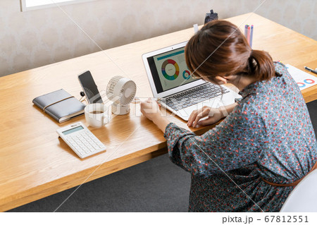 テレワーク中に卓上扇風機をセッティングする若い女性 67812551