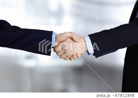 Business people shaking hands, close-up. Group of unknown businessmen standing in a modern office. Teamwork, partnership and handshake concept 67812898