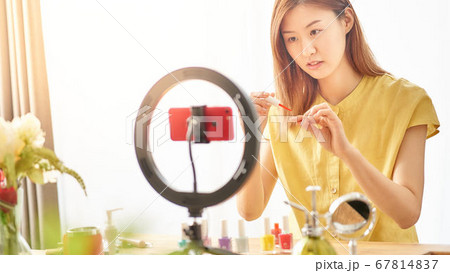 スマホカメラの前で化粧品を紹介する若い女性 スマホカメラの前で化粧品を紹介する若い女性 67814837