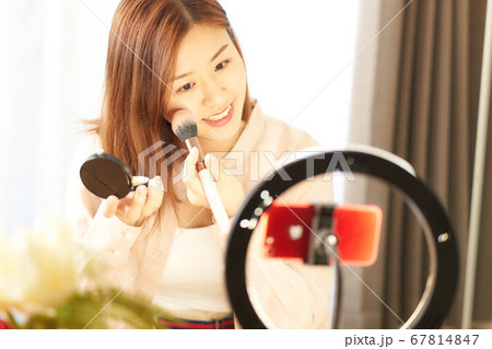スマホカメラの前でお化粧をする若い女性 スマホカメラの前でお化粧をする若い女性 67814847