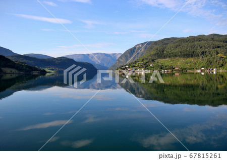 ノルウェー　ハダンゲルフィヨルド、ウルヴィク地区、早朝の山々とすがすがしい水面と空の風景を望むワイド 67815261