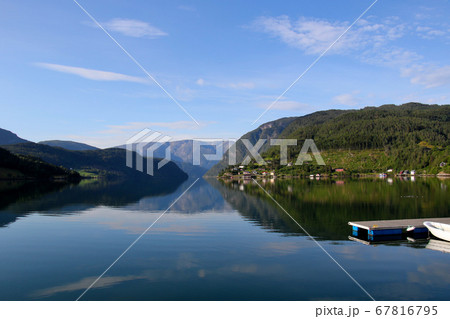 ノルウェー　ハダンゲルフィヨルド、ウルヴィク地区、さわやかな早朝の山々と水面と空の風景を望む　ロング 67816795