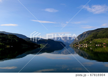 ノルウェー　ハダンゲルフィヨルド、ウルヴィク地区、さわやかな早朝の山々と水面と空の風景を望む　遠景 67816904
