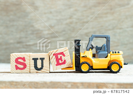 Toy forklift hold letter block e to complete word sue on wood background 67817542