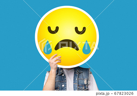 Unrecognizable man hiding his face behind crying sad emoticon emoji Unrecognizable man hiding his face behind crying sad emoticon emoji 67823026