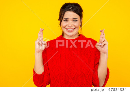 Woman in sweater wish something standing in the yellow studio isolated. Woman in sweater wish something standing in the yellow studio isolated. 67824324