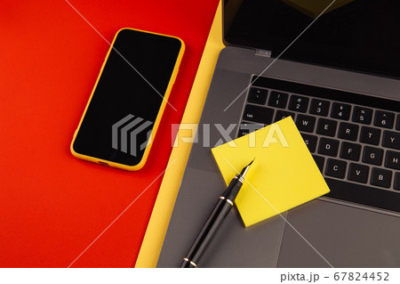 Home office workplace desk concept. Laptop, smartphone and sticky note on red background 67824452