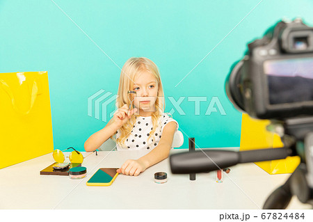 Happy girl at home speaking in front of camera for vlog. Little kid working as blogger, recording video tutorial for Internet. Happy girl at home speaking in front of camera for vlog. Little kid working as blogger, recording video tutorial for Internet. 67824484
