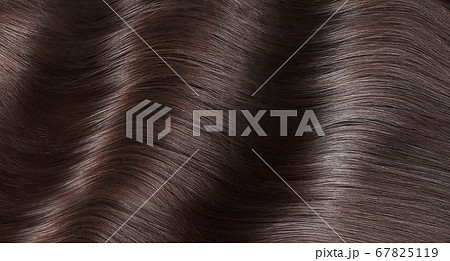 A closeup view of a bunch of shiny straight brown hair in a wavy curved style 67825119