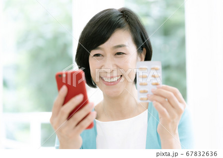 スマホとクスリを見るミドル女性 67832636