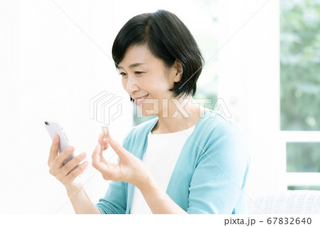 スマホとクスリを見るミドル女性 67832640