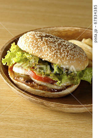 丸い木皿に盛り付けてある照り焼きバーガーとポテトフライ 丸い木皿に盛り付けてある照り焼きバーガーとポテトフライ 67834385