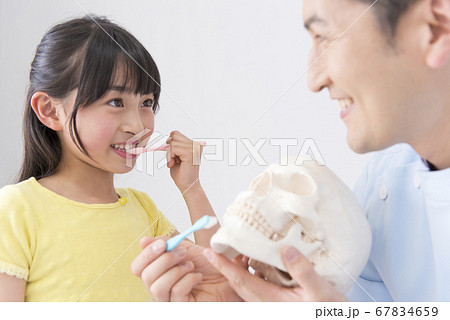 女の子に歯磨き指導をする男性歯科医 67834659