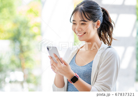 屋外でスマホを操作する若い女性 67837321