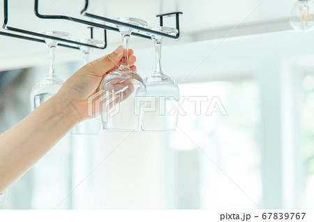 明るい部屋でグラスホルダーからワイングラスを取り出す　wineglass glass 67839767