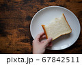 食パンをつかんだ手と食器と机 67842511