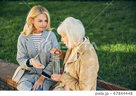 Mature lady feeling ill near female friend in the park 67844448