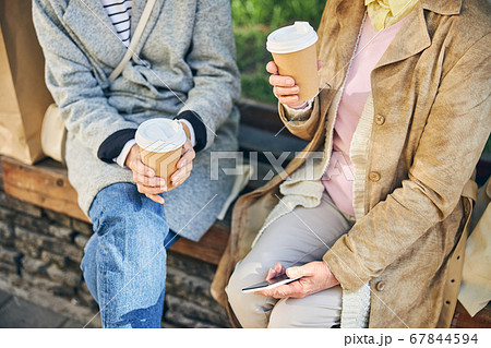 Good looking women sitting on the bench and talking about good weather Good looking women sitting on the bench and talking about good weather 67844594