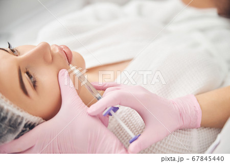 Calm young woman getting cosmetic facial treatment 67845440