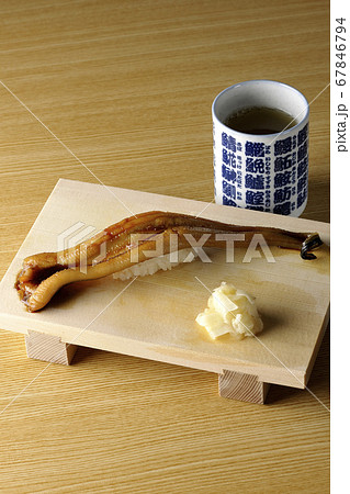 寿司下駄の上の穴子一本握りとお茶 67846794