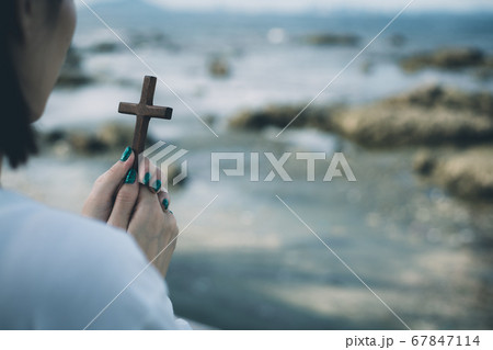 Asian woman praying with wooden cross on the beach Asian woman praying with wooden cross on the beach 67847114