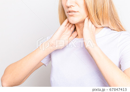 Female checking thyroid gland by herself. Close up of woman in white t- shirt touching neck with red spot. Thyroid disorder includes goiter, hyperthyroid, hypothyroid, tumor or cancer. Health care. Female checking thyroid gland by herself. Close up of woman in white t- shirt touching neck with red spot. Thyroid disorder includes goiter, hyperthyroid, hypothyroid, tumor or cancer. Health care. 67847413