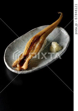 お皿の上に盛り付けられた炙り煮穴子の一本握り(黒背景) お皿の上に盛り付けられた炙り煮穴子の一本握り(黒背景) 67848121