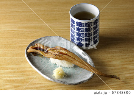 お皿の上に盛り付けられた炙り煮穴子の一本握りとお茶 67848300